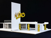 Modell mit goldener Skulptur an der Wand und goldenen Brückenpfosten