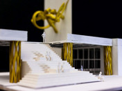 Modell mit goldener Skulptur an der Wand und goldenen Brückenpfosten
